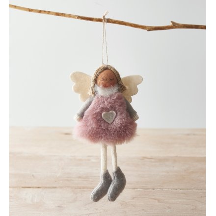 Decorative angel figurine with pink fur dress and heart pendant hanging on a branch.