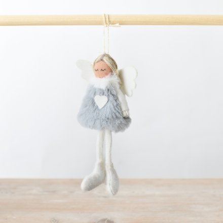 Decorative angel figurine with gray fur and white heart on a wooden surface and light background