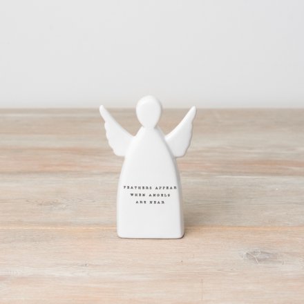 White angel figurine with text on a wooden surface