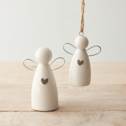 Two white angel figurines with heart details on a wooden surface.