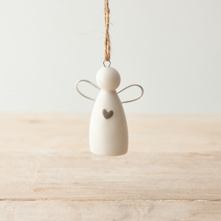 White ceramic angel ornament with a heart on a wooden surface