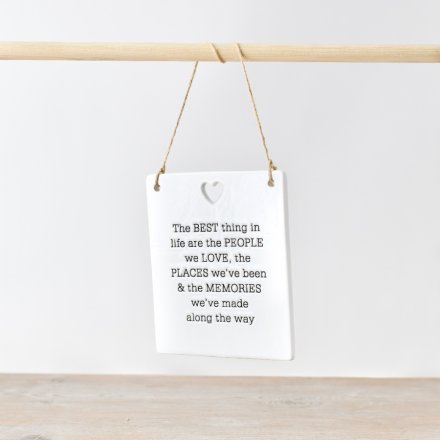 Ceramic rectangle hanging sign with the quote 'The best thing in life are the people we love, the places we've been, and the memories we've made along the way'. Above the quote is a heart cut out from the sign. 