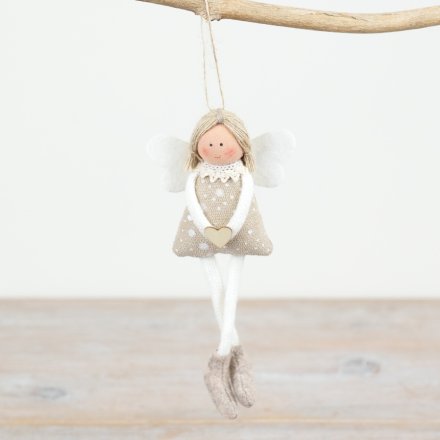 Small doll with a heart pendant hanging from a branch on a light background