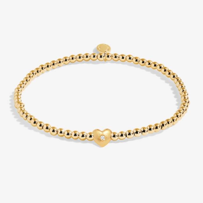 Gold bracelet with a heart-shaped charm on a white background