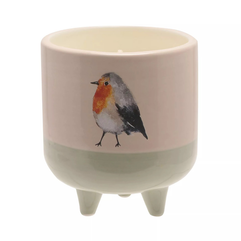 cylindrical ceramic jar holding a candle inside with three little feet to stand on. Bottom half of the candle is a light green and the top half is white. On the front it features a watercolour robin illustation.