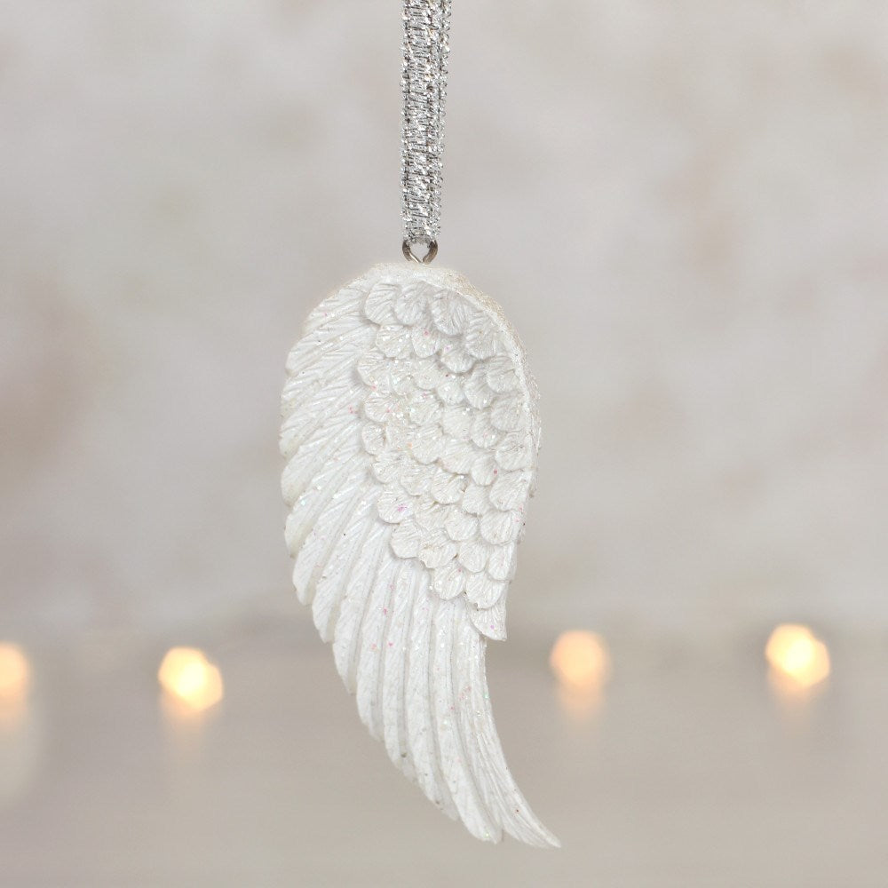 Singular angel wing hanging by silver ribbon on a blurred background.