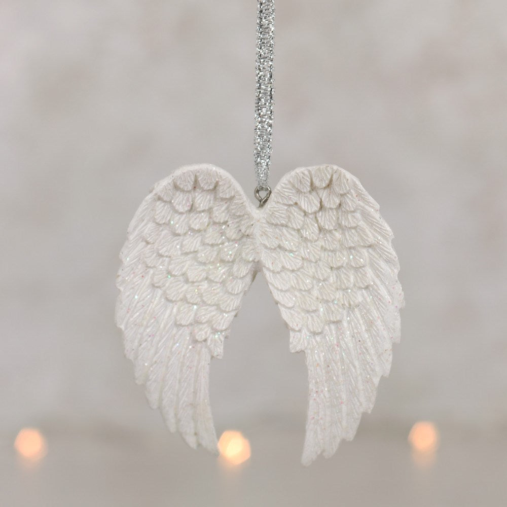 White angel wings ornament hanging against a soft, blurred background