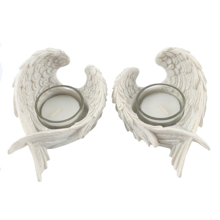 Two white angel wing candle holders with candles inside on a white background