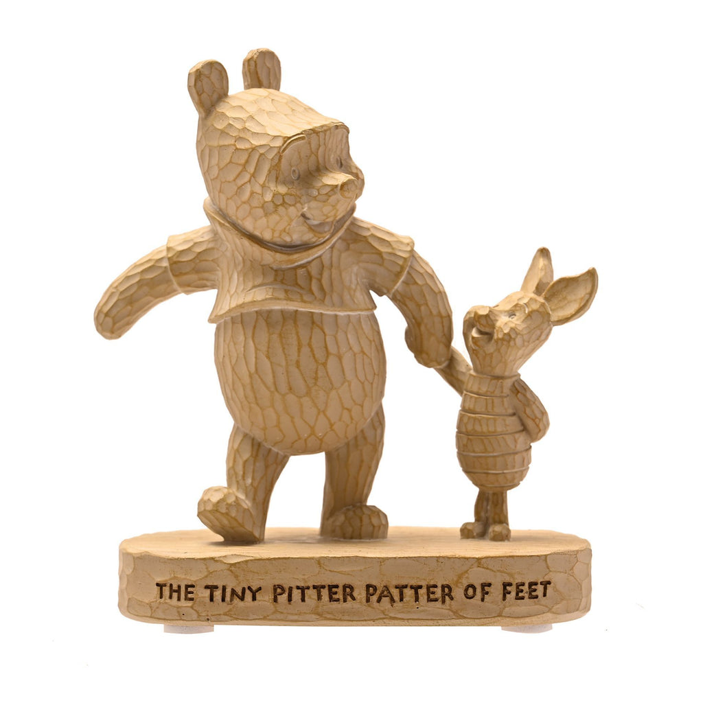 wood-carved look, resin figurine of Winnie the Pooh and Piglet smiling, looking at each other, and holding hands. Figurines stood on a wooden-carved effect base with the phrase 'the tiny pitter patter of feet' engraved into the front. 
