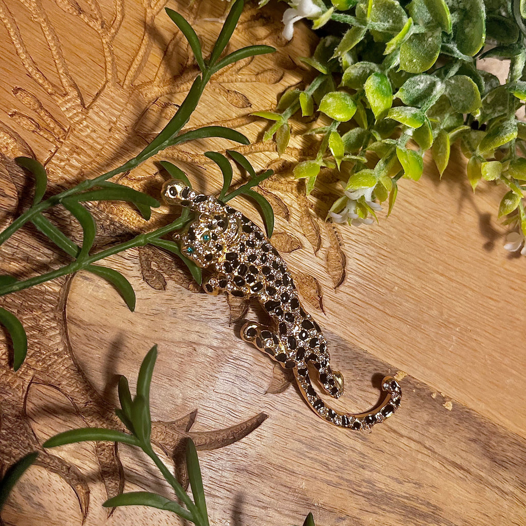 Crawling leopard gold brooch with clear rhinestones and black crystals for the fur and emerald coloured rhinestones for eyes.