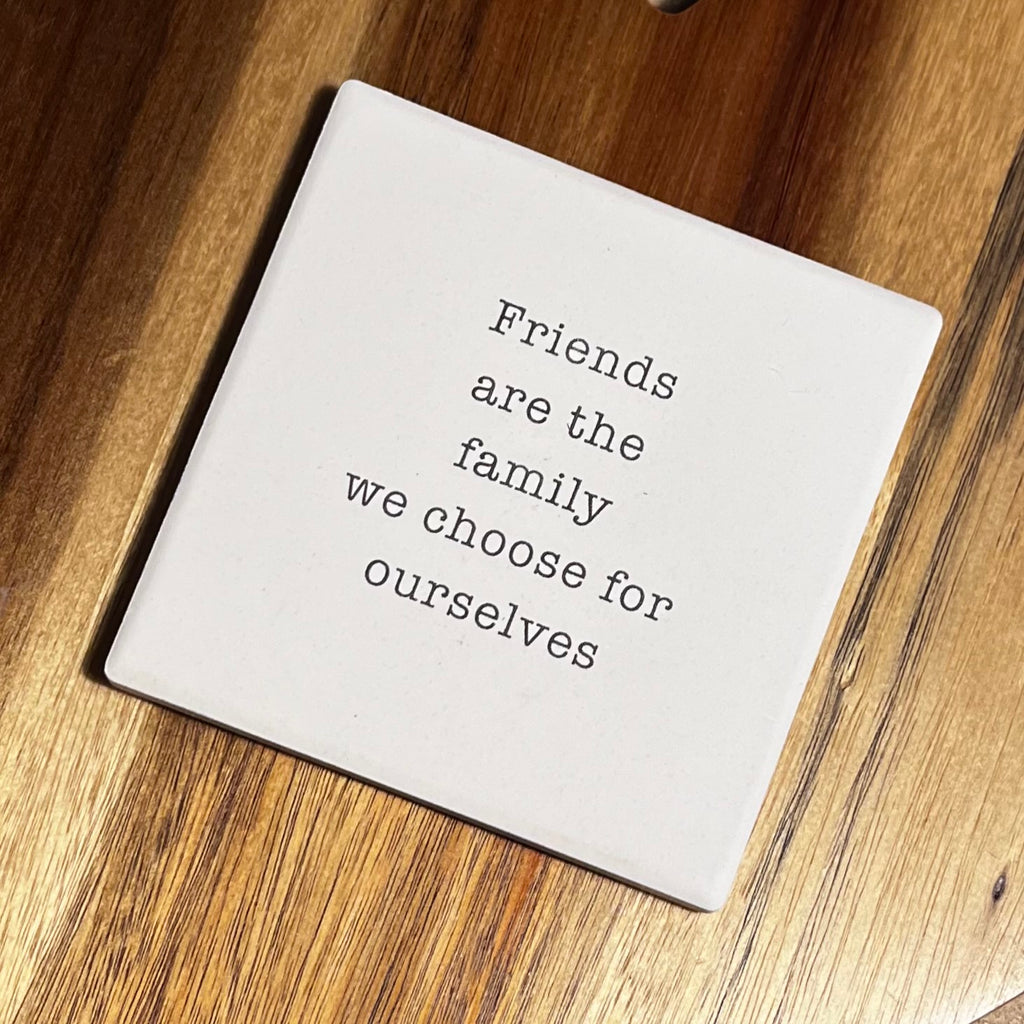 Square white coaster with the quote 'friends are the family we choose for ourselves' in typewriter font