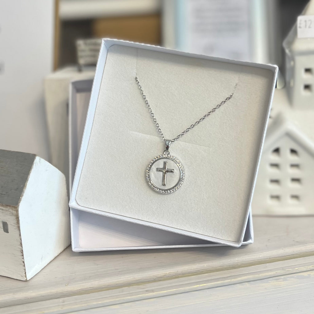Silver chain necklace with a circle pendant. Features crystals around the circumference of the pendant, a pearlescent background inside the pendant and a silver cross in the middle.