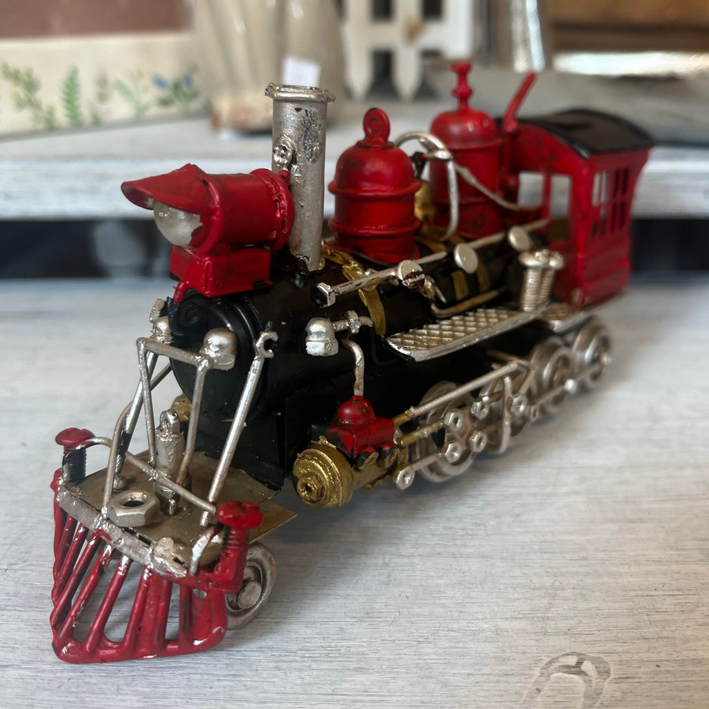 Vintage model train with steam engine with black painted body and silver and red accents. 