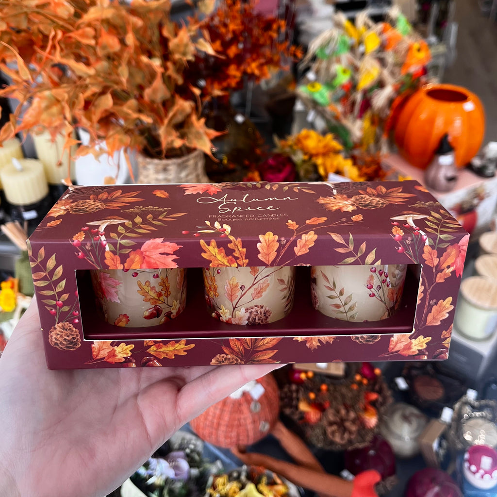 Set of 3 candles in autumnal packaging with leafy autumnal background.