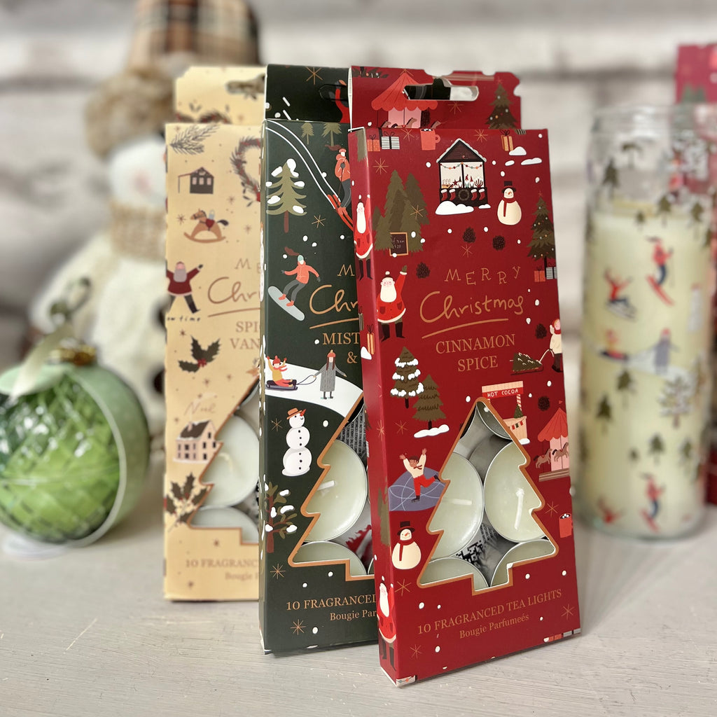 Packaged Christmas-themed tea lights with decorative designs on a neutral background