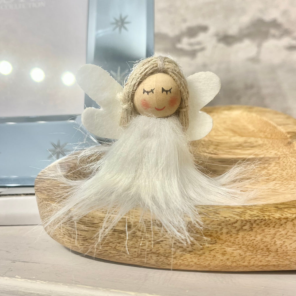 Small angel figurine with white wings and beard on a wooden surface
