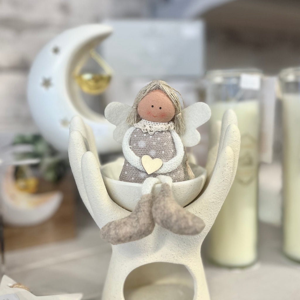 angel decoration sitting in bowl with cupped hands and a blurred background