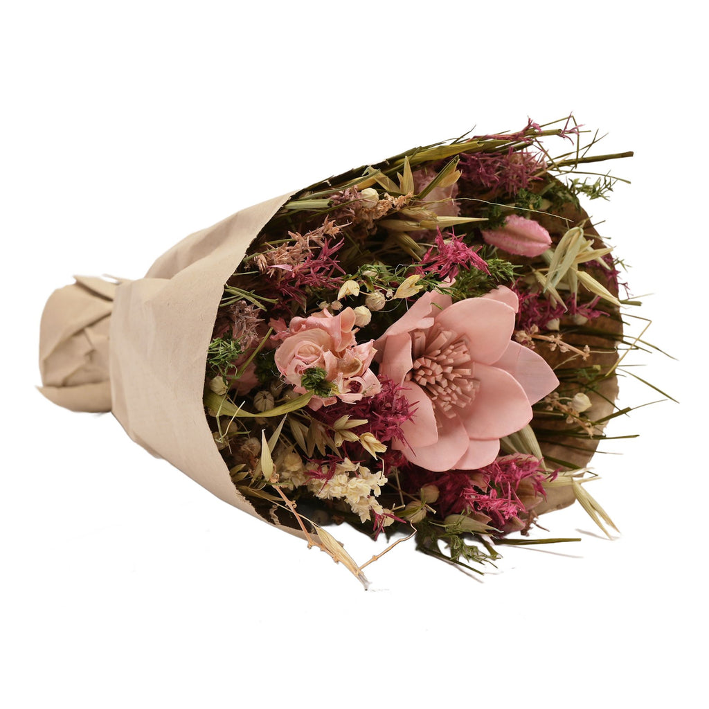 Faux floral bouquet wrapped in brown paper featuring misc leaves and flowers in pink, purple, white, and green with one big pink flower.