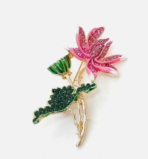 Pink lotus flower brooch with a gold stem and a green leaf covered in matching colour rhinestones. 