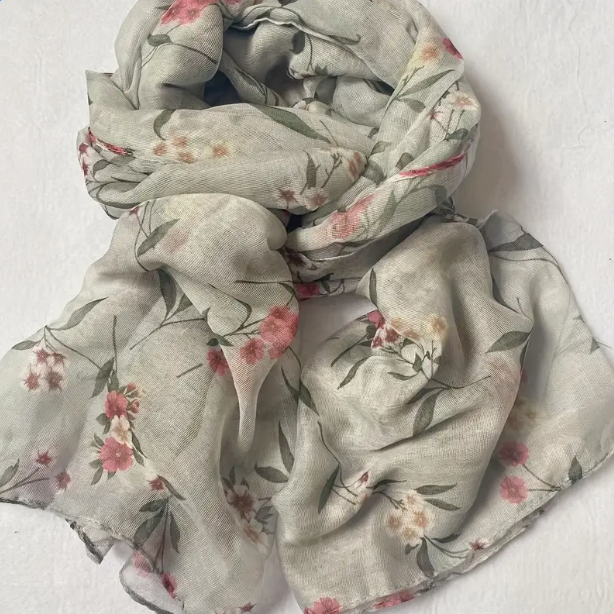 Grey scarf with pink and white flowers sporadically placed on the design.