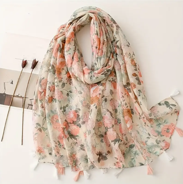 Cream floral scarf featuring pink flowers with green leaves. Watercolour effect. Alternating pink and white tassels on the bottom of the scarf edges.