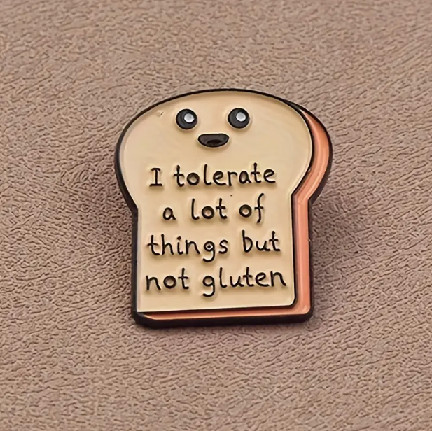 Slice of bread shaped pin with a smiley face at the top. Underneath the smiley face is the quote 'I tolerate a lot of things but not gluten'