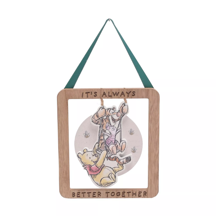 Wooden rectangle frame border with the quote 'it's always better together' engraved on. Inside the frame is a wooden image with Tigger and Piglet hanging on a swing with the swing connecting to the twine that connects it to the wooden border, and Winnie the Pooh hanging on the bottom of the swing. 