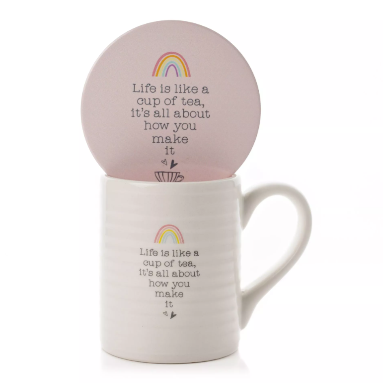 White, horizonally ribbed mug with pink interior and quote 'Life is like a cup of tea, it's all about how you make it' printed on the front in typewriter font. Above the quote is a little rainbow illutration. Bwlow the quote is two little hearts. Features a pink circle coaster with the same design. 