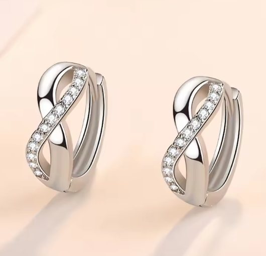 silver hoop earrings with infinity symbol aligned with hoop ring. The crossover section of the infinity sign features crystals. 