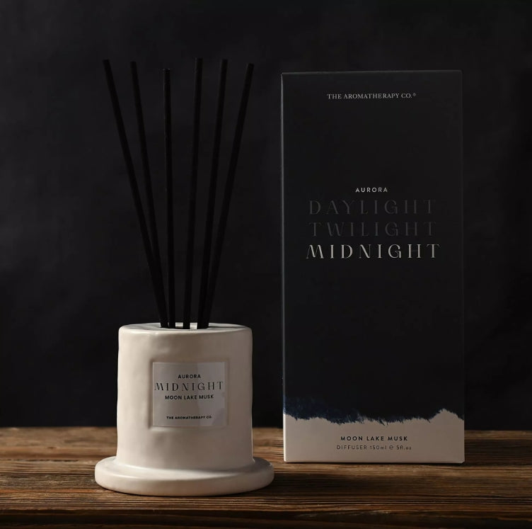 Diffuser with black sticks and packaging labeled 'Aromatherapy Co.' on a wooden surface.