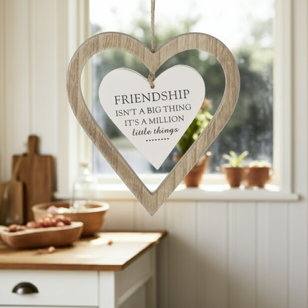 Heart-shaped wooden plaque with 'Friendship isn't a big thing, it's a million little things' quote in a kitchen setting.