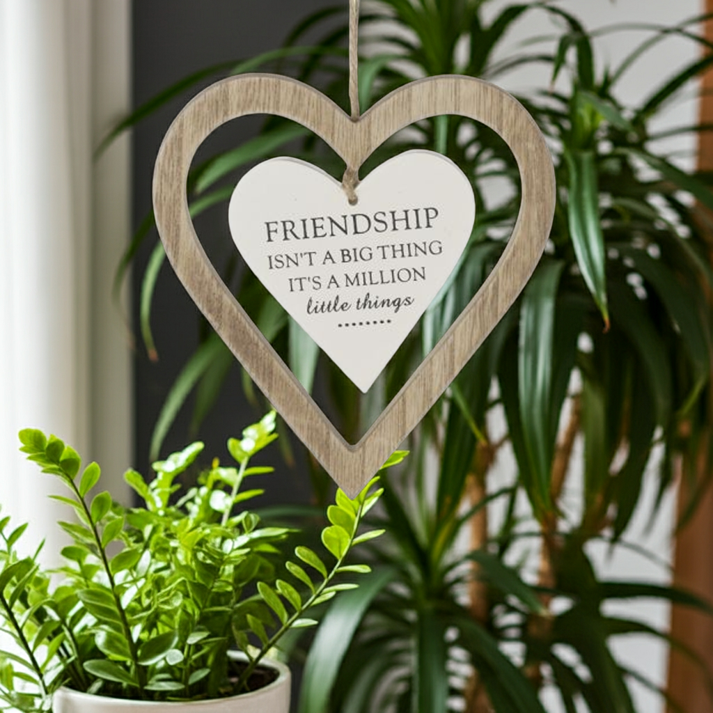 Heart-shaped wooden sign with a motivational quote on a plant background