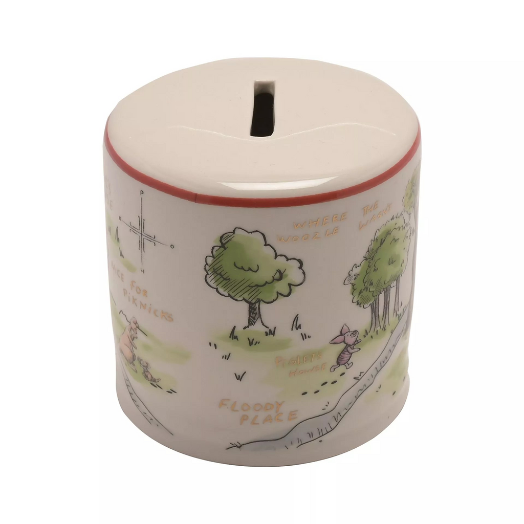 White cylindrical money box with coin slot at the top and red band around the top of the side. Features hundred acre wood illustrations around the sides of the money box. Features Winnie the Pooh and friends characters: Winnie the Pooh, Piglet, Rabbit, Kanga and Roo, Owl, Tigger, and Eeyore.